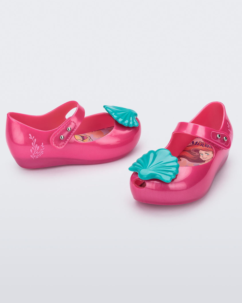 Angled view of a pair of pink Mini Melissa Ultragirl + Disney Little Mermaid flats with blue shell on top