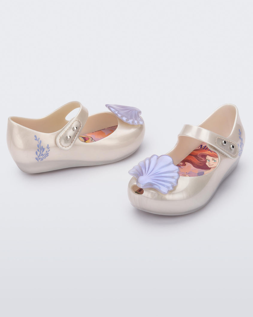 Angled view of a pair of pearly white Mini Melissa Ultragirl + Disney Little Mermaid flats with pearly blue shell on top