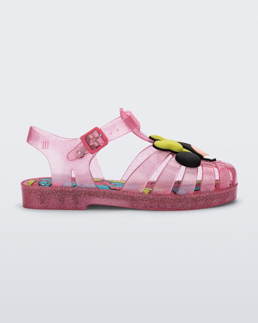 Side view of a clear pink glitter Mini Melissa Possession + Disney 100 sandal with Mickey on one foot and Minnie on another foot.