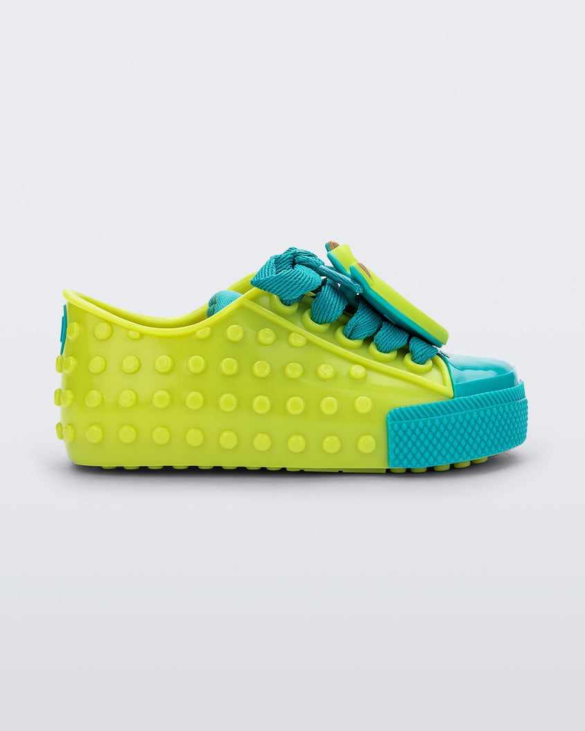 Side view of a baby green Melissa Polibolha sneakers with a blue toe top and Disney Monsters Inc Mike.