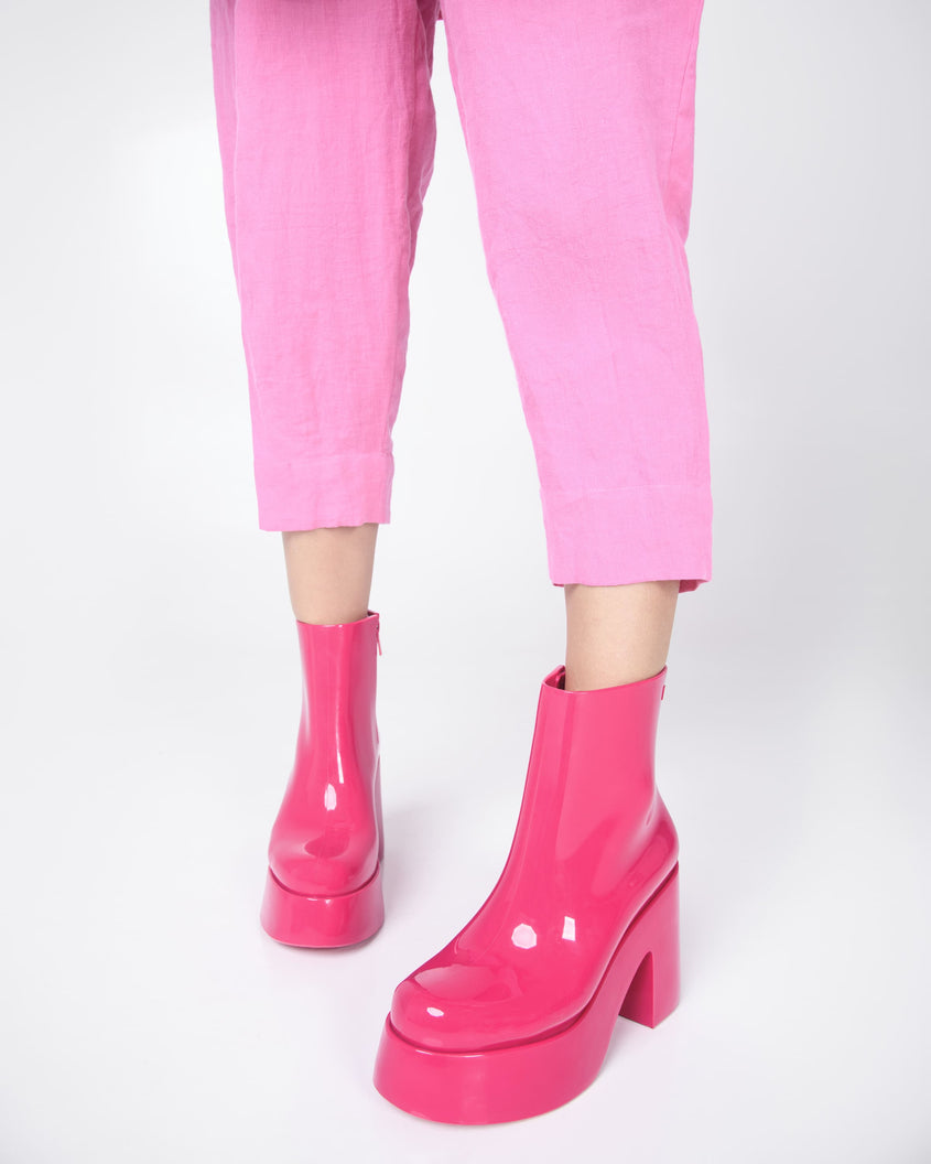 A model's legs in pink capris wearing a pair of pink Melissa Nubia platform heel boots.