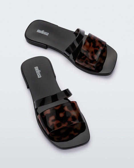 Top angled view of a pair of black and tortoise Ivy women's slide