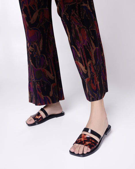 Model's legs in pants wearing a pair of a black and tortoise Ivy women's slide