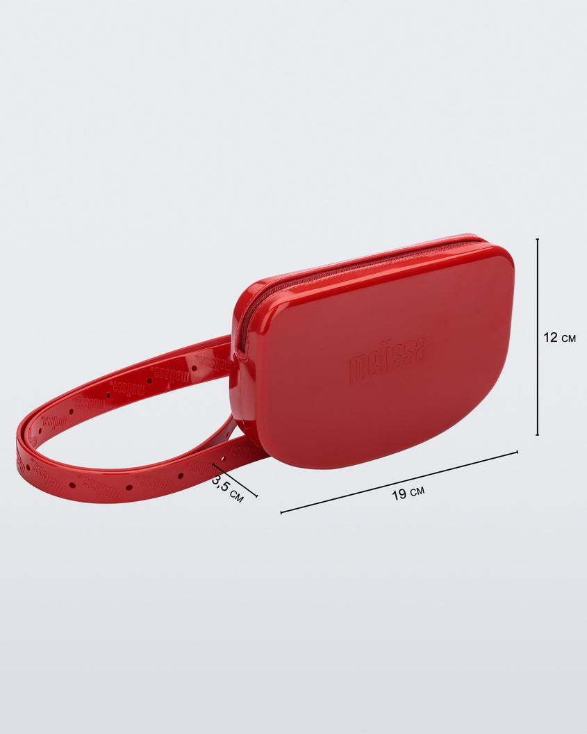 Angled view of the red Melissa Go Easy Bag with strap with bag dimensions 19 cm length, 3.5 cm width, and 12 cm height.
