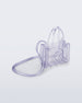 Angled view of a clear Melissa Small Jelly Shopper + Telfar bag with handles and a body strap