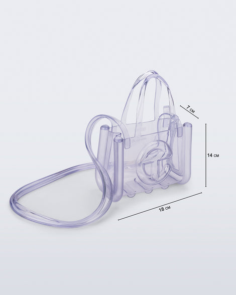 Angled view of a clear Melissa Small Jelly Shopper + Telfar bag with handles and a body strap with dimensions, 18 cm length, 7 cm width, 14 cm height 
