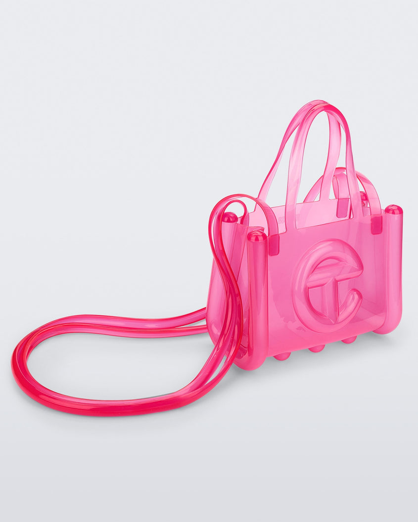 Angled view of a pink small Melissa Jelly Shopper bag + Telfar bag with a handle and straps.