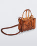 Angled view of a brown small Melissa Jelly Shopper bag + Telfar bag with a handle and straps.