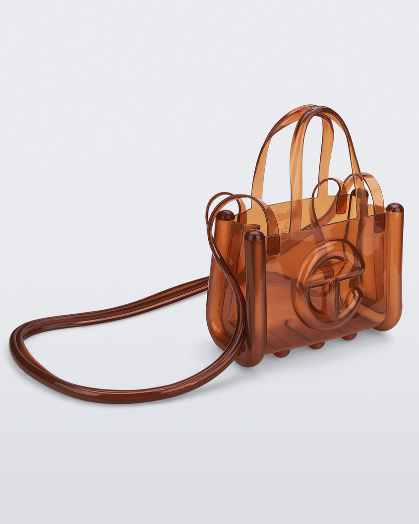 Angled view of a brown small Melissa Jelly Shopper bag + Telfar bag with a handle and straps.