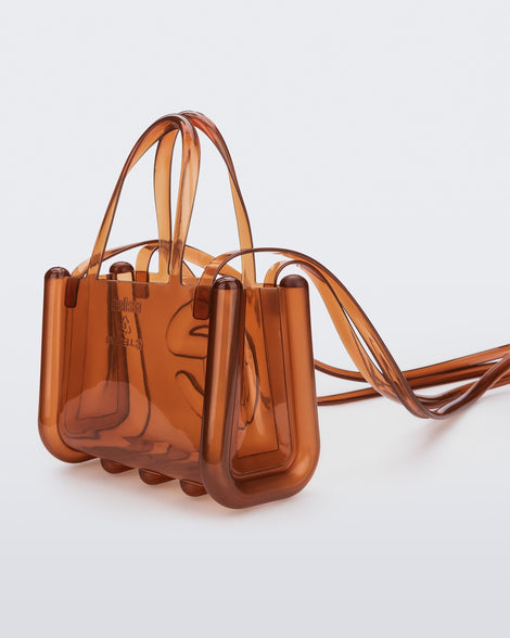 Angled view of a brown small Melissa Jelly Shopper bag + Telfar bag with a handle and straps.