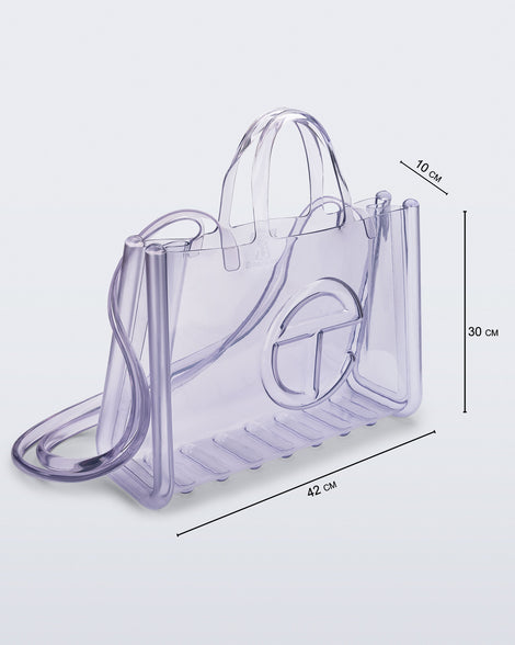 Angled view of a clear Melissa Large Jelly Shopper + Telfar bag with handles and a body strap with dimensions, 42 cm length, 10 cm width, 30 cm height 