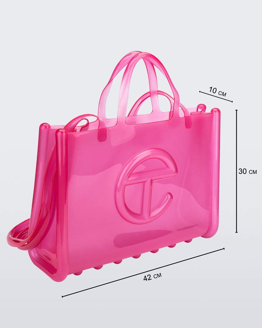 Angled view of a pink large Melissa Jelly Shopper bag + Telfar bag with a handle and straps. Dimensions 42 cm length, 10 cm width, 30 cm height