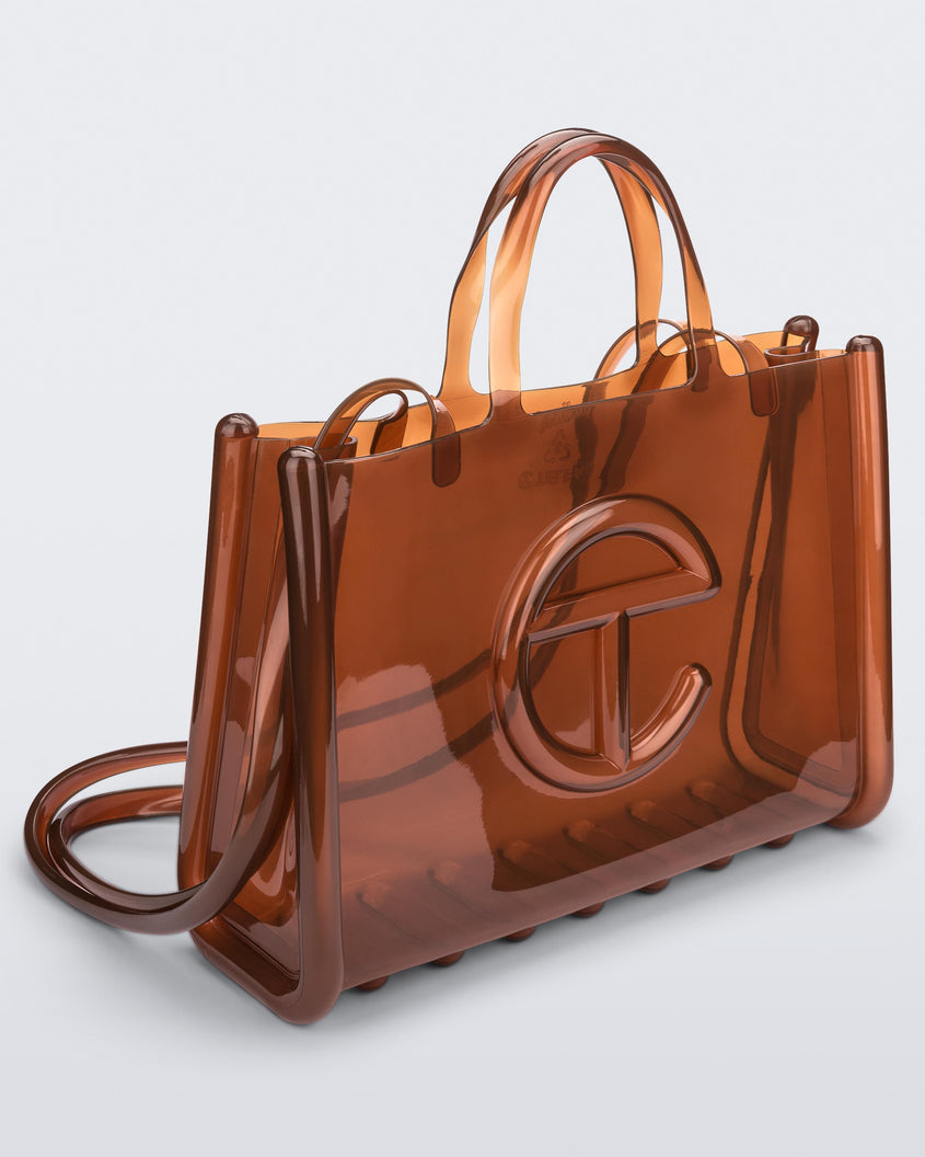 Angled view of a brown large Melissa Jelly Shopper bag + Telfar bag with a handle and straps.