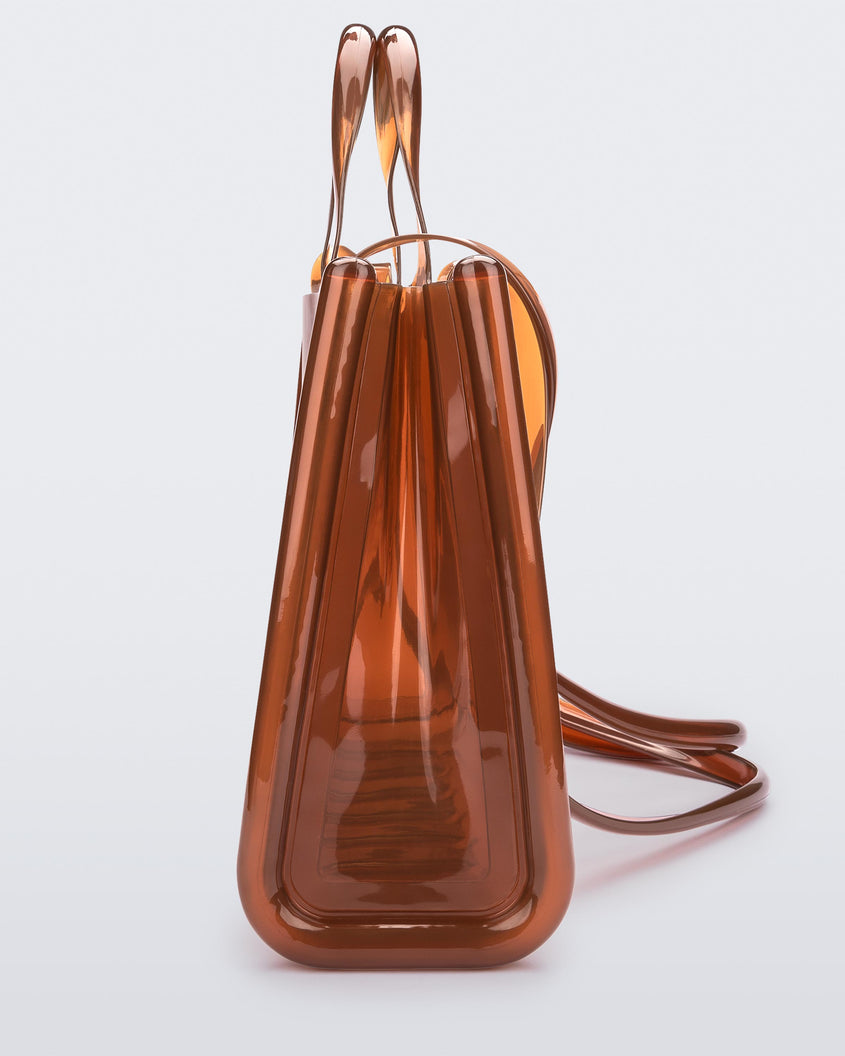 Side view of a brown large Melissa Jelly Shopper bag + Telfar bag with a handle and straps.