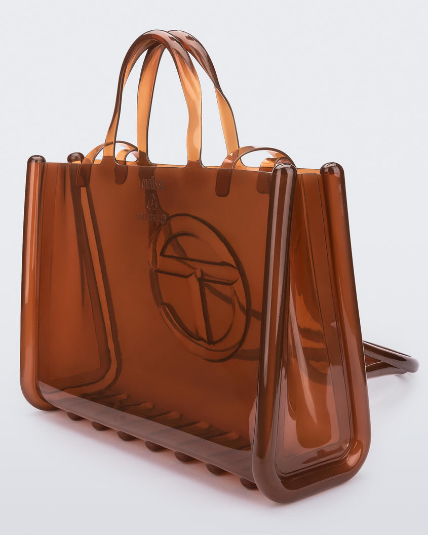 Angled view of a brown large Melissa Jelly Shopper bag + Telfar bag with a handle and straps.