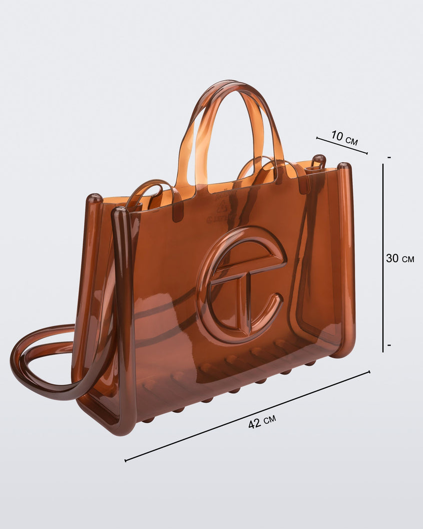 Angled view of a brown large Melissa Jelly Shopper bag + Telfar bag with a handle and straps. Dimensions 42 cm length, 10 cm width, 30 cm height