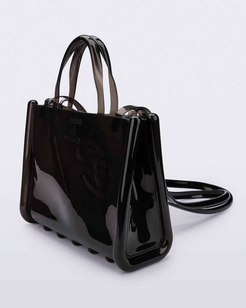 Angled view of a black medium Melissa Jelly Shopper bag + Telfar bag with a handle and straps.