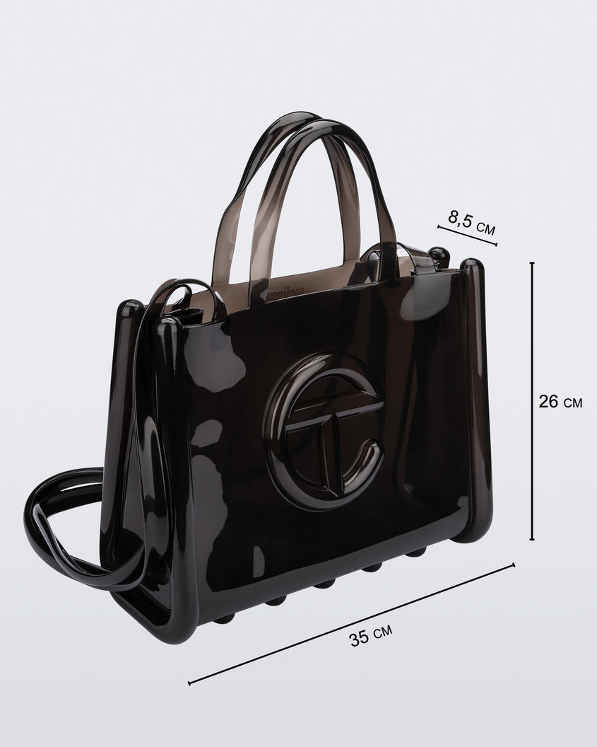 Angled view of a black medium Melissa Jelly Shopper bag + Telfar bag with a handle and straps. Dimensions 35 cm length, 8.5 cm width, 26 cm height