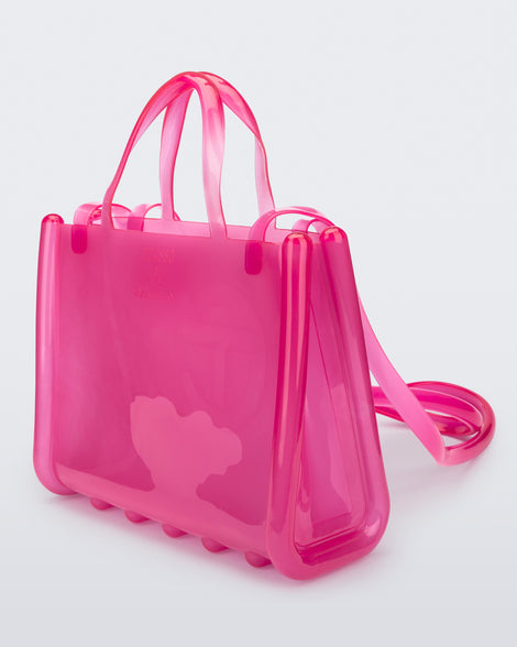 Angled view of a pink medium Melissa Jelly Shopper bag + Telfar bag with a handle and straps.