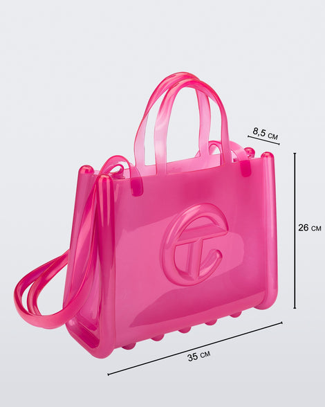 Angled view of a pink medium Melissa Jelly Shopper bag + Telfar bag with a handle and straps. Dimensions 35 cm length, 8.5 cm width, 26 cm height