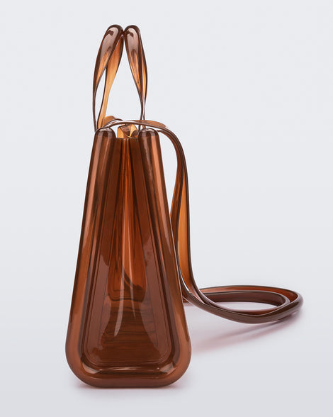 Side view of a brown medium Melissa Jelly Shopper bag + Telfar bag with a handle and straps.