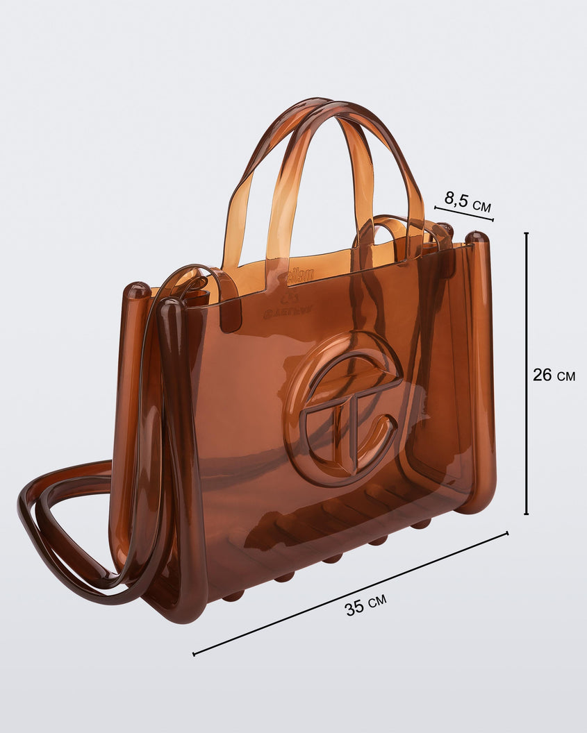 Angled view of a brown medium Melissa Jelly Shopper bag + Telfar bag with a handle and straps. Dimensions 35 cm length, 8.5 cm width, 26 cm height