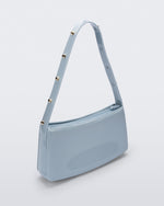 Angled view of the blue Melissa Baguete Studs bag with a short studded strap.