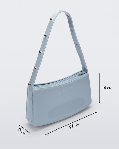 Angled view of the blue Melissa Baguete Studs bag with a short studded strap, showing dimensions, 27 cm length, 6 cm width, and 14 cm height.