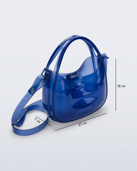 Angled view of a clear blue Mirror bag with cross body straps two clear handles with bag dimensions 21cm x 7cm x 16xm