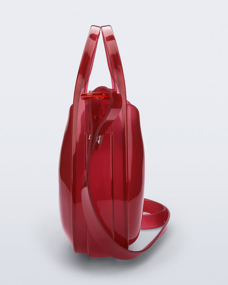 Side view of a clear red Mirror bag with cross body straps two clear handles.