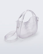 Angled view of a clear Mirror bag with cross body straps two clear handles.