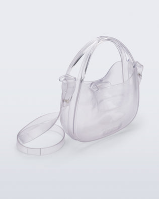 Angled view of a clear Mirror bag with cross body straps two clear handles.