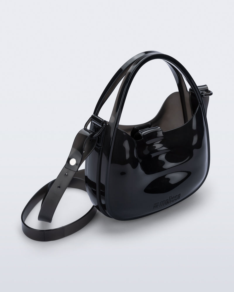 Angled view of a clear black Mirror bag with cross body straps two clear handles.