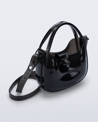Angled view of a clear black Mirror bag with cross body straps two clear handles.