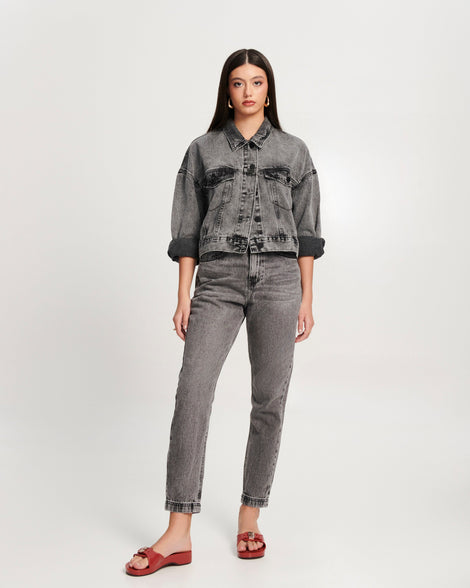 Model in black jean pants and jacket wearing a pair of red Pescura Heel + Scholl slides with top buckle