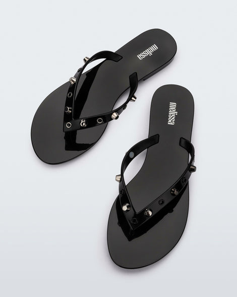 Top view of a pair of black Melissa Harmonic Studs flip flops with gold studs on the upper.