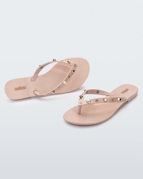 Angled and top view of a pair of pink Melissa Harmonic Studs flip flops with gold studs on the upper.