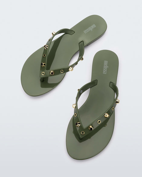 Top view of a pair of green Melissa Harmonic Studs flip flops with gold studs on the upper.
