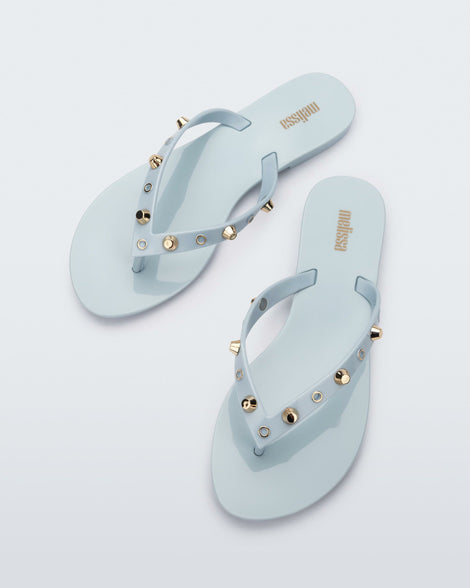 Top view of a pair of blue Melissa Harmonic Studs flip flops with gold studs on the upper.