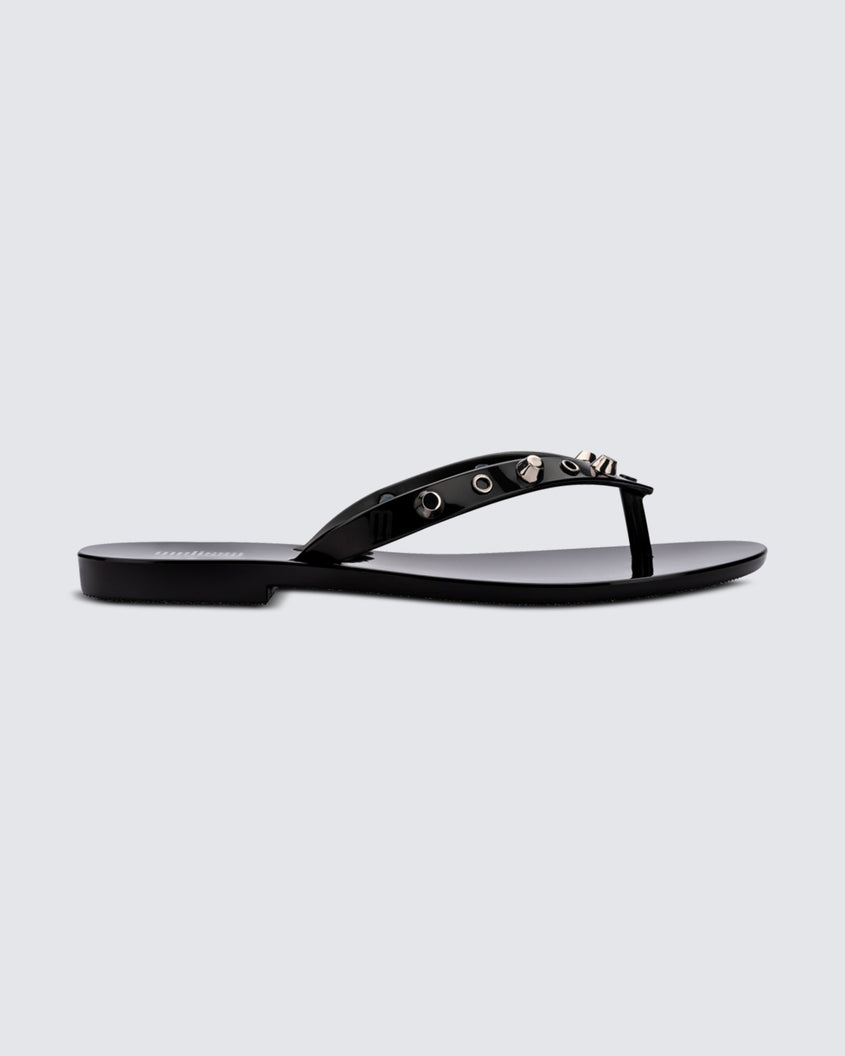 Side view of a black Melissa Harmonic Studs flip flop with gold studs on the upper.
