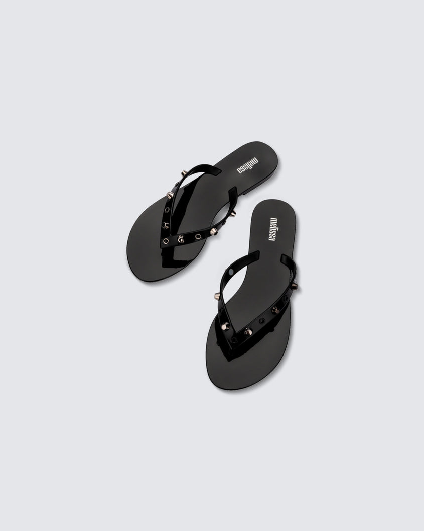Top view of a pair of black Melissa Harmonic Studs flip flops with gold studs on the upper.