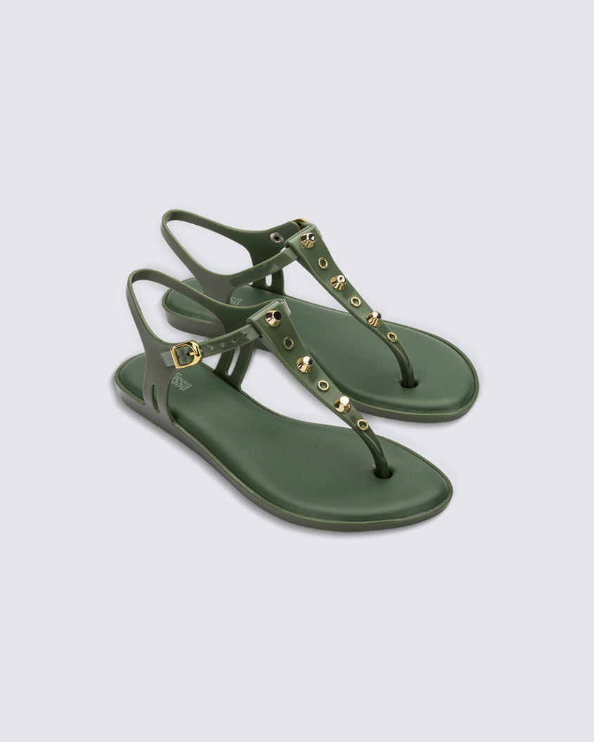 Angled view of a pair of green Melissa Solar studs sandals with gold studded t-strap and gold buckle.