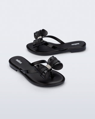Side and angled view of a pair of black Slim Flip Flops with bow