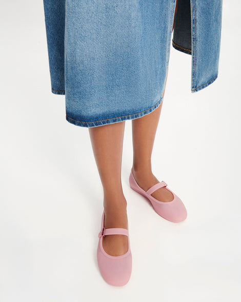 Model's legs in a jean skirt wearing a pair of milky pink Soft Ballerina flats with a strap and buckle