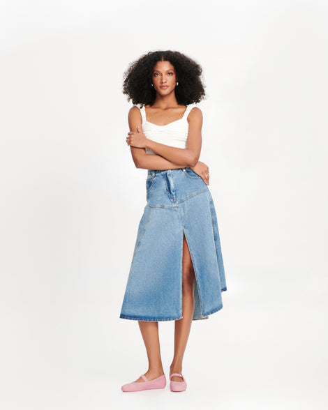 Model in a jean skirt and white tank wearing a pair of milky pink Soft Ballerina flats with strap and buckle. 