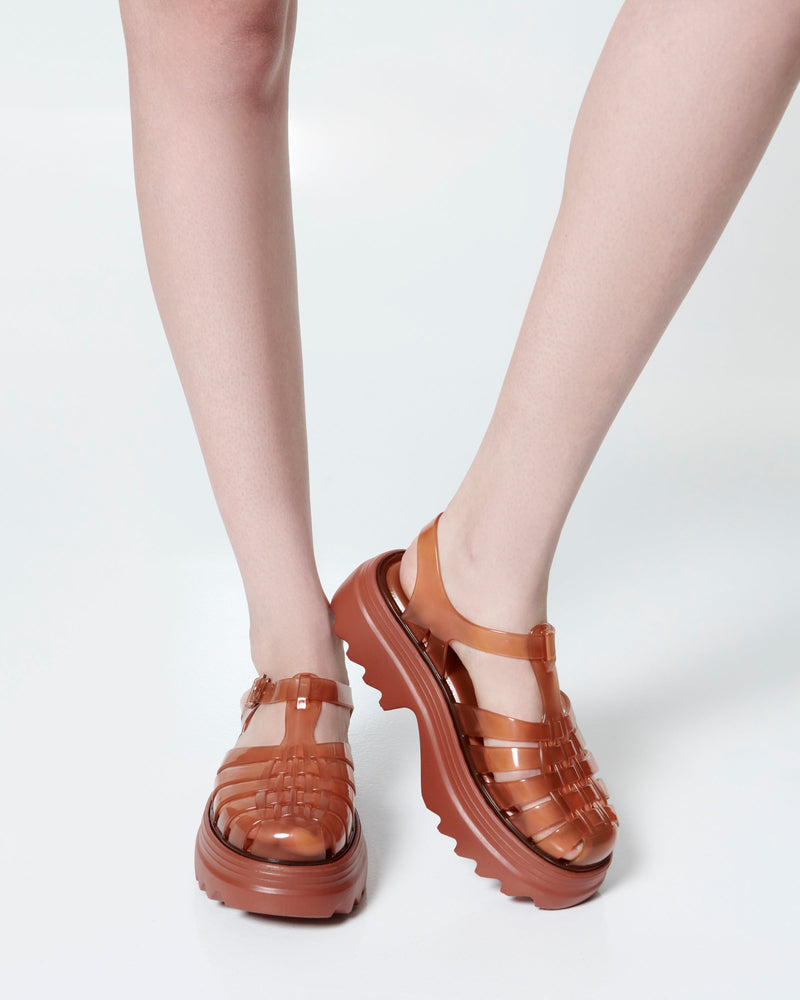 Model's legs wearing a pair of transparent brown Possession Platform II fisherman sandals
