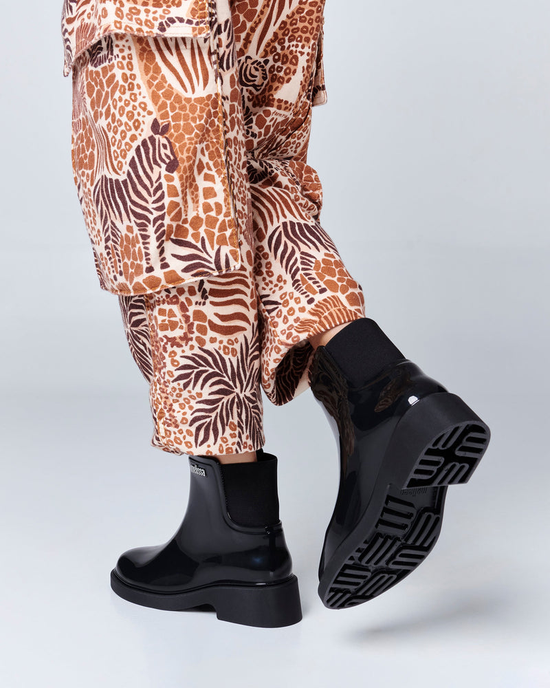 Model's legs in patterned pants wearing a pair of black Chelsea Boots.