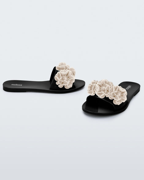Side and angled view of a pair of black Babe Springtime women's slide with 3 beige flowers.