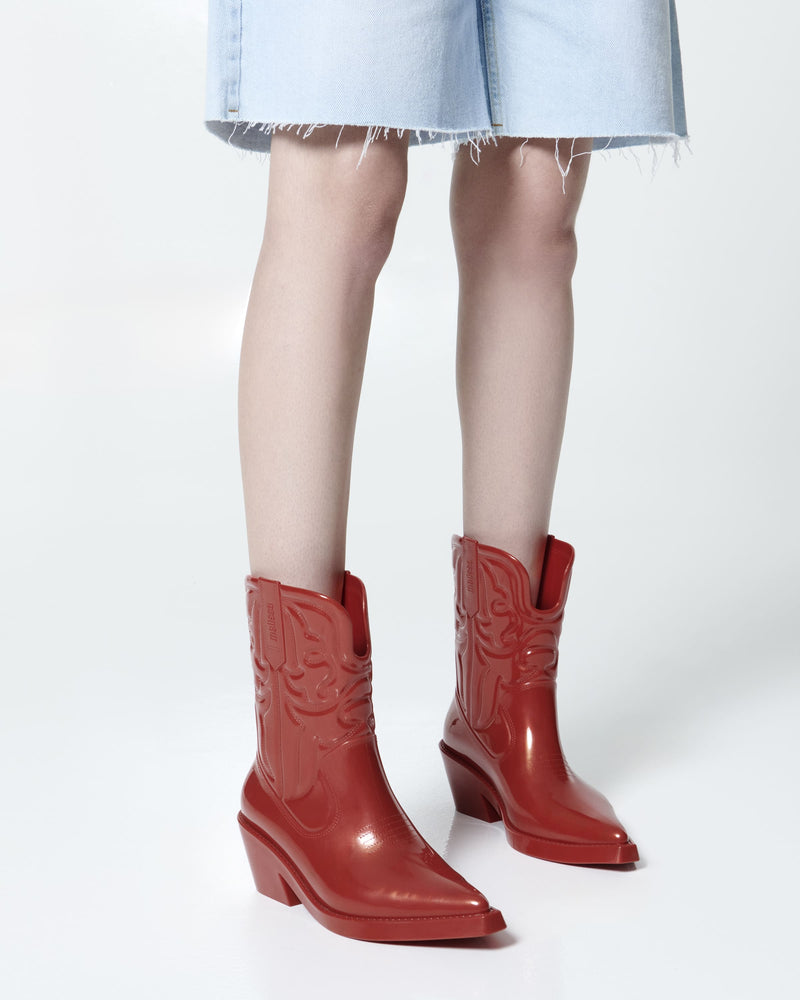 Model's lets in long jean shorts wearing a pair of red Texas boots with pointed toe.