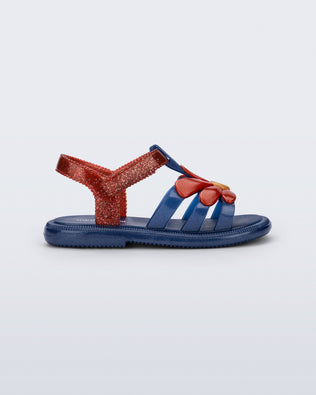 Side view of a glitter blue Hip Bloomy baby sandal with red daisy on top and red straps